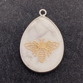 Macro shot of waterdrop white stone pendant with gold bee inlay and silver frame - Bee