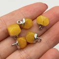 Set of 5 faceted yellow natural stone pendants with silver metal clasps held by hand - Ginger Yellow Stone