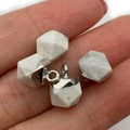 Faceted white stone pendants with silver clasps shown in hand for scale and detail - Howlite