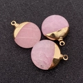 Macro detail of three pink natural stone round pendants with gold-plated metal loops - Rose Quartz
