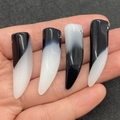 Handheld view of four black and white agate horn pendants with smooth polished finish - Black Gradient Tooth Style
