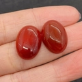 Deux cabochons en cornaline rouge ovale présentés sur la peau pour l'échelle réelle - 13x18mm / Agate rouge