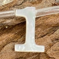 Detailed macro view of number one shaped white shell bead with horizontal hole on dark wood - Number 1 / 6x10mm, 1g