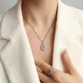 Collar con colgante Fu plateado y anillo tejido en una modelo con blazer blanco - Plateado