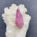 Makroaufnahme eines unregelmäßigen rosa Naturkristall-Anhängers auf weißem Hintergrund - Rosa