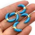 Main tenant quatre pendentifs turquoise en forme de croissant avec accents dorés - Turquoise Bleue