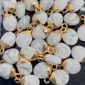Macro-opname van witte natuurstenen hangers met gouden sluitingen op zwarte basis - Howliet / 8x14mm