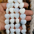 Nahaufnahme von durchscheinenden weißen Opal-Herzperlen in der Hand für DIY-Schmuck - 16x16x8mm (~12 Stück/Packung) / Opal