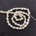 Macro shot of natural freshwater baroque pearls with soft luster on a black textured background - 3-4mm / Milky White