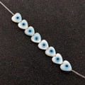 Macro detail of heart-shaped shell beads with blue evil eye pattern for DIY jewelry - Heart-Shaped 6mm / White