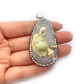 Pendentif goutte en pierre bleue avec coquillages et strass tenu à la main - Blanc