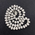 Detailed view of white turquoise abacus beads necklace with silver lobster clasp on black background - Howlite