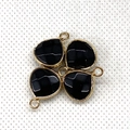 Close-up of four faceted black teardrop gemstone pendants with golden metal frames and rings - Black Agate