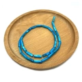 Blaue zylindrische Süßwassermuschelperlen 4x13mm spiralförmig auf einem Holzteller - Blau