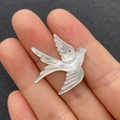 Detailed view of hand-held swallow-shaped white mother of pearl pendant for DIY jewelry - Single Item / White Shell