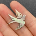 Macro view of a bird-shaped iridescent shell pendant held by hand showing craft details - Single Item / Black Shell