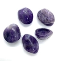 Détail de cinq pierres d'améthyste polies dans différentes nuances de violet sur blanc - Améthyste