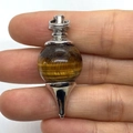 Spherical tiger eye stone pendant with silver metal connector shown in hand - 18x41mm / Tiger's Eye