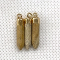 Three bullet-shaped natural stone pendants with golden metal caps and loops on white background - Picture Jasper