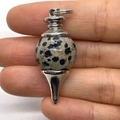 Handheld view of a Dalmatian Jasper stone pendulum pendant with silver metal findings - 18x41mm / Dalmatian Jasper