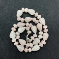 Detailed view of teardrop rose quartz beads with a lobster clasp on a dark grey background - Rose Quartz