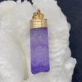 Macro view of purple faceted crystal pendant with gold textured metal cap on white stones - Lapis Lazuli
