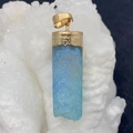 Macro view of light blue natural crystal druzy pendant with gold-plated textured edges - Black Agate