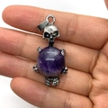 Gothic silver skull pendant with a round purple amethyst stone held in skeleton hands - Purple Crystal