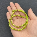 Green and brown emperor stone round beads for DIY jewelry held in a palm for scale - No.11 (Green Brown Yellow Texture)