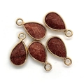 Detail showing five teardrop goldstone pendants with polished metallic gold edges - Gold Sandstone