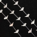 Makro-Detail von weißen schillernden Muschel-Vogel-Perlen für DIY-Schmuck auf Schwarz - Vogelform (Nr. 4)