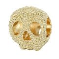 Makro-Detail einer goldenen Totenkopfperle mit körniger Textur für DIY-Schmuck - Gold