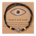 Detail eines handgewebten schwarzen Evil Eye Armbands mit Goldperlen auf Displaykarte - Schwarz