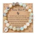 Close-up of blue-purple emperor stone beads with heart and baby feet pendants on card - Amazonite