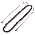 Detail of beaded necklace featuring dark wood discs and black lava stones with adjustable cord - Necklace