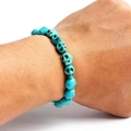 Detail of blue skull-shaped turquoise beads on an elastic bracelet worn on wrist - Sky Blue Skull Style (02)
