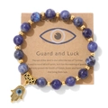 Détail du bracelet en perles bleues avec breloque main de Fatma dorée et œil - Style Pierre à Veines Bleues (CCA174)