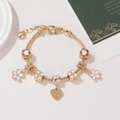 Detail of gold beaded bracelet with cherry blossom charms and heart-shaped filigree pendant - White Sakura Flower Pendant 17cm