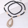 Collana lunga bohémien con perline nere e ciondolo a goccia dorato su legno - Goccia Bianco