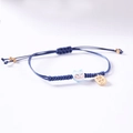 Detailopname van donkerblauw geweven armband met gelukskat-kraal en gouden hanger - Zhaocai Stijl / Blauw