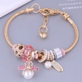 Goldenes DIY-Bettelarmband mit Bienenanhänger rosa Kristallen und Perlen auf grau - Rosa