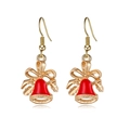 Detailopname van kerstklok oorbellen met rood emaille en gouden metalen afwerking - Kerstbel