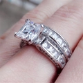 Macro shot of princess cut square crystal ring set with pavé diamonds on finger - US 6 / Silver