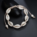 Detailed view of handmade seashell bracelet with adjustable woven rope on a black stone - White Woven Rope Style / White Rope