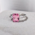 Elegant silver three-stone ring with a rectangular pink gemstone and clear side stones - US 6 / White Gold