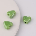 Detailansicht von drei glänzenden grünen Keramikherzperlen für DIY-Schmuck - Hellgrün