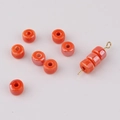 Macro shot of orange glazed ceramic donut beads with smooth finish for DIY jewelry crafts - Orange Red