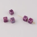 Macro detail of five purple square ceramic beads with central holes for DIY jewelry - Purple
