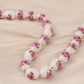 Detalle macro de cuentas de cerámica blanca con motivos florales morados para joyas - Estilo 12#