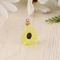 Macro shot of miniature yellow resin XO bottle pendant with gold ring on wood - Yellow